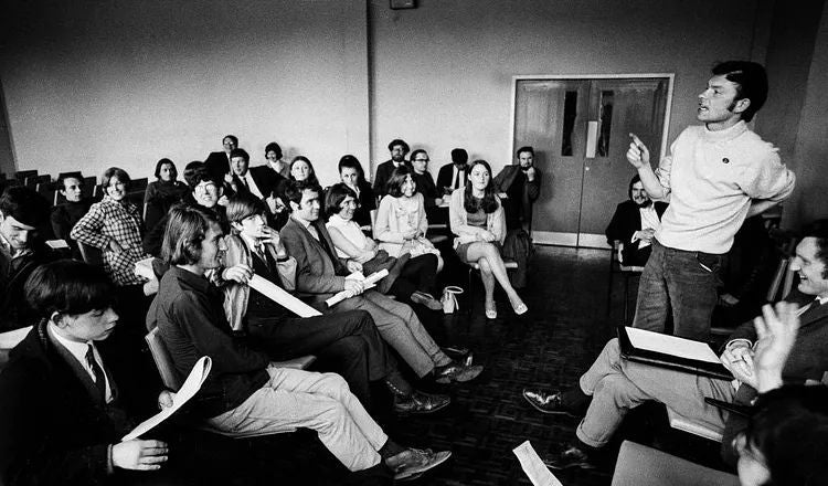A speaker addresses a seated audience during a discussion, illustrating themes of public speaking, storytelling, communication, and audience engagement explored in Elliot Ackerman's essay A Man Should Know: How to Speak from the Heart.