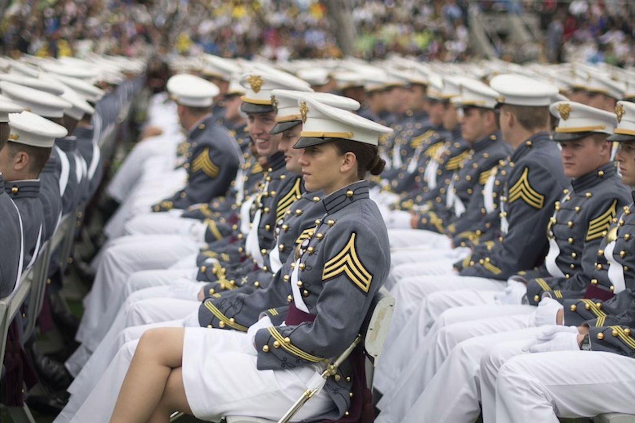 West Point cadets in full dress gray uniforms sit in formation during a United States Military Academy ceremony.