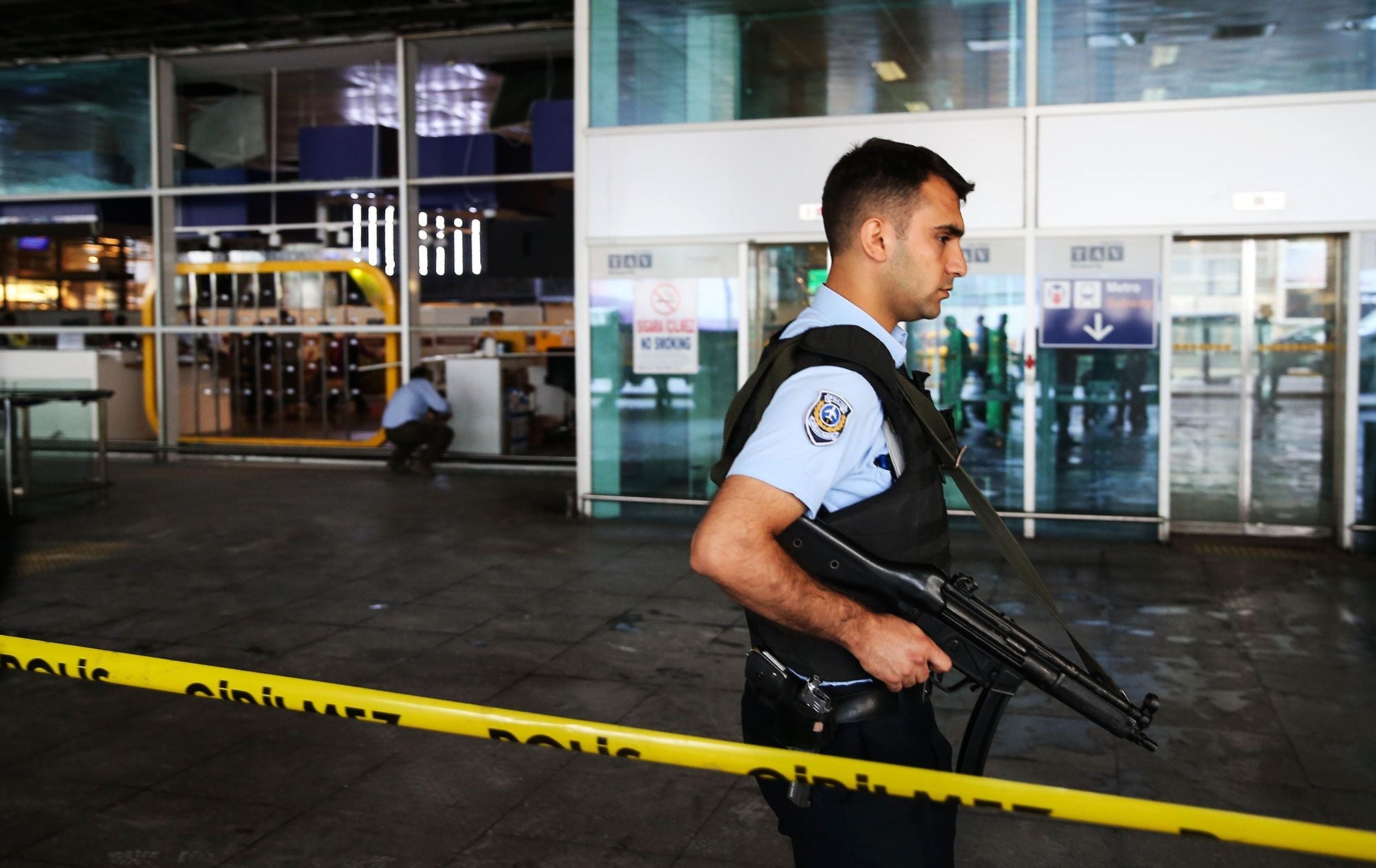 A Turkish police officer stands guard behind police tape at Atatürk Airport's damaged terminal.
