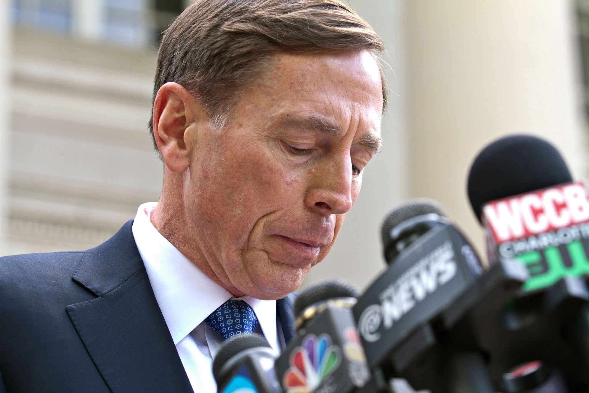 David Petraeus stands before a bank of press microphones outside a Charlotte courthouse.