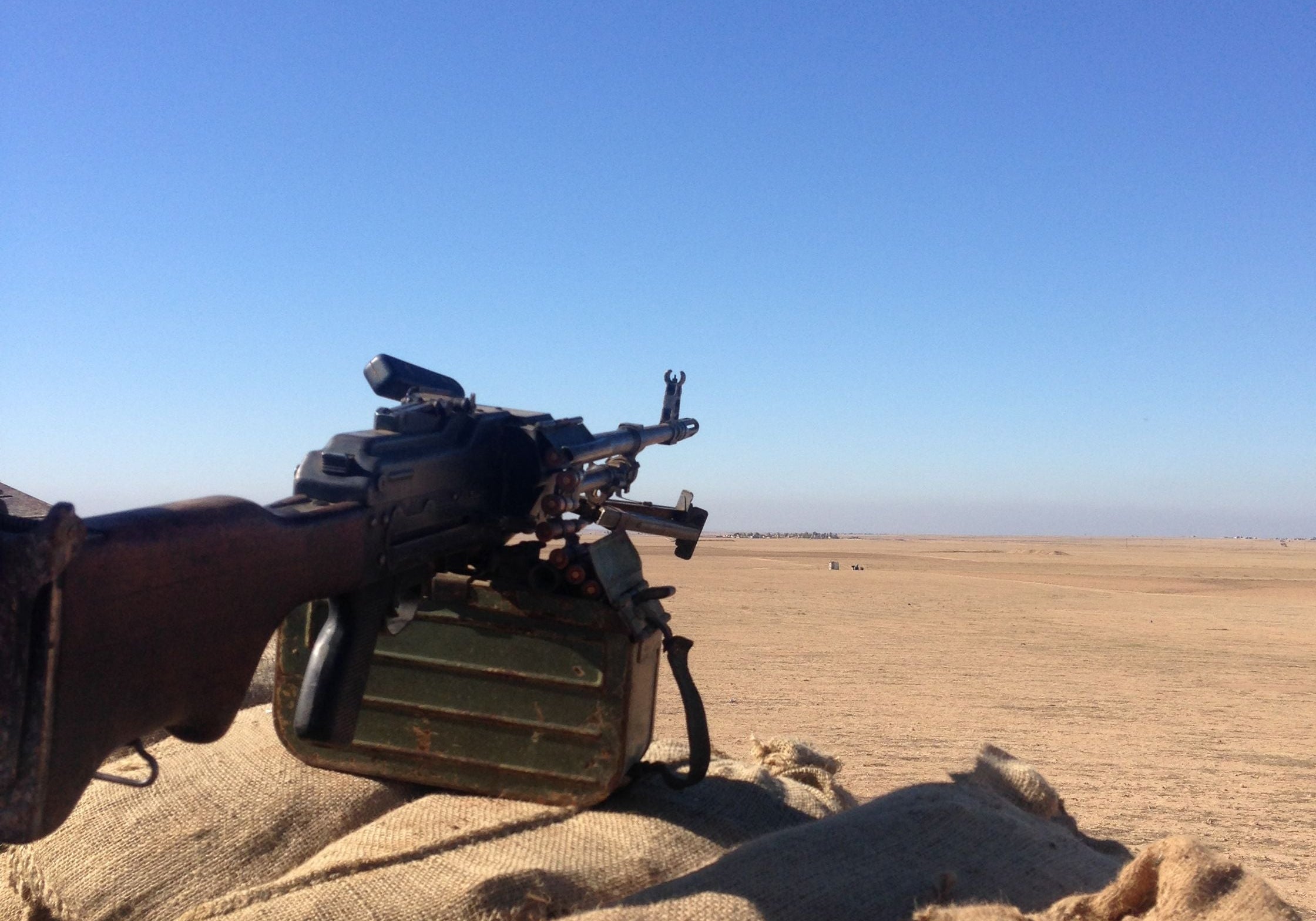 A PKM machine gun mounted on sandbags at a peshmerga front-line position, overlooking the desert toward ISIS positions.