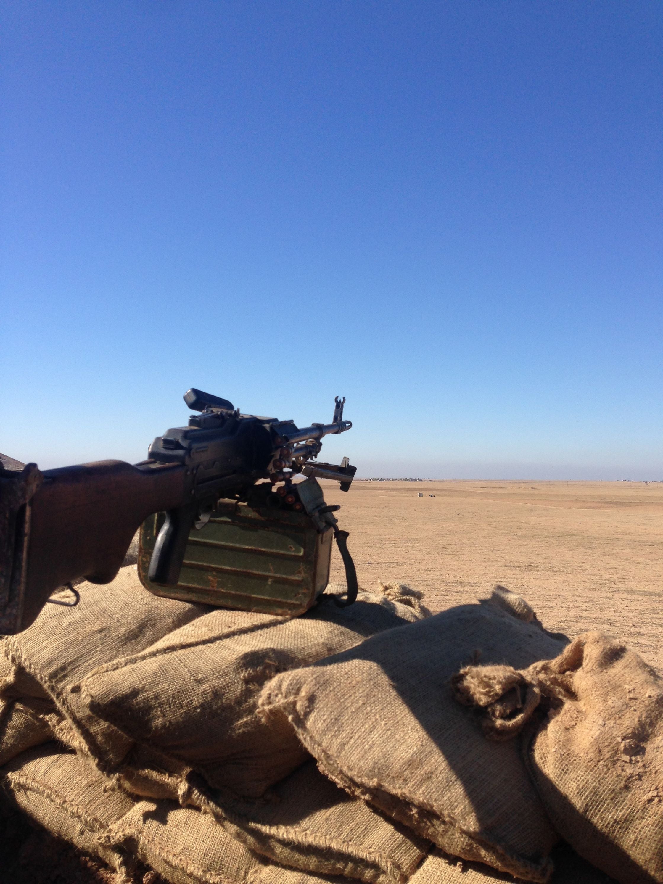 A PKM machine gun mounted on sandbags at a peshmerga front-line position, overlooking the desert toward ISIS positions.