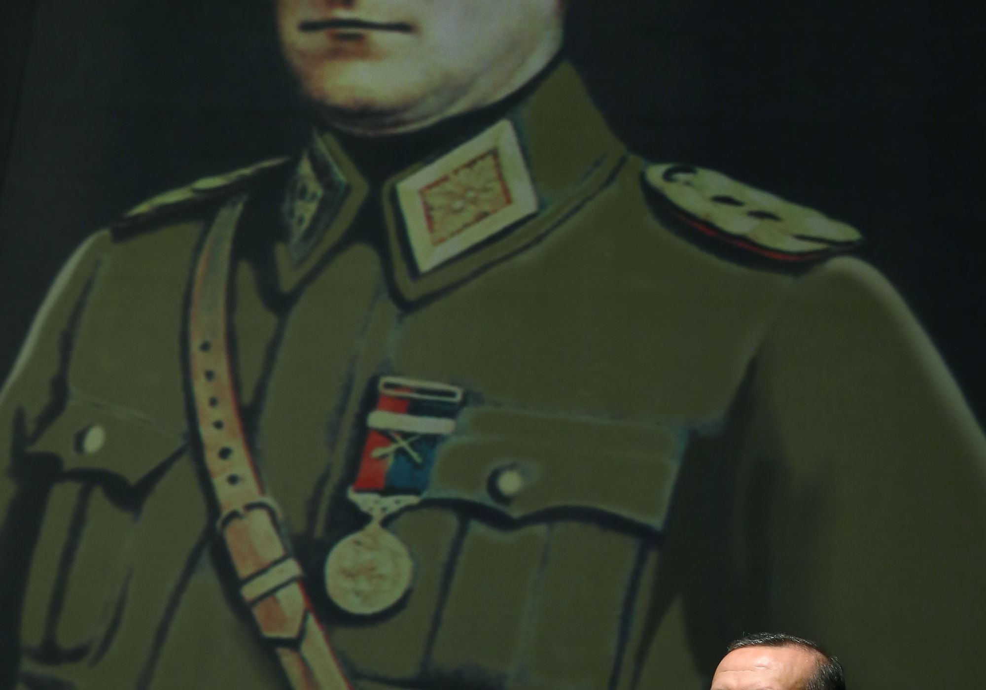 President Erdoğan speaks at a podium beneath a large portrait of Atatürk in military uniform.
