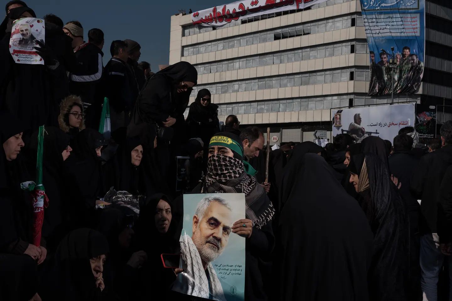 Crowds gather in Tehran to mourn Iranian General Qassem Soleimani, with mourners holding portraits of Soleimani and banners honoring him during a public funeral procession following his death.