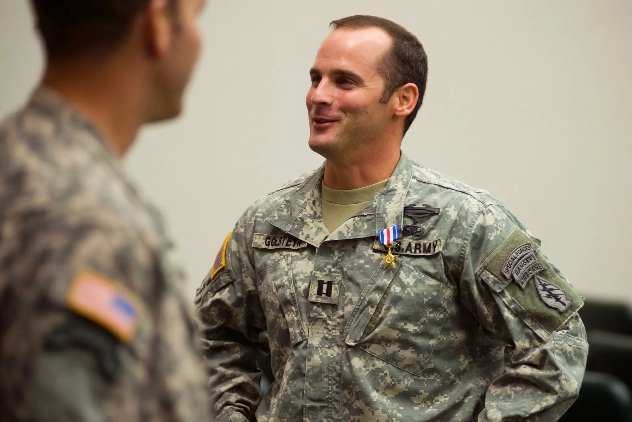 U.S. Army Special Forces officer Maj. Mathew Golsteyn, wearing Army combat uniform and military decorations, speaks with another soldier during a ceremony.