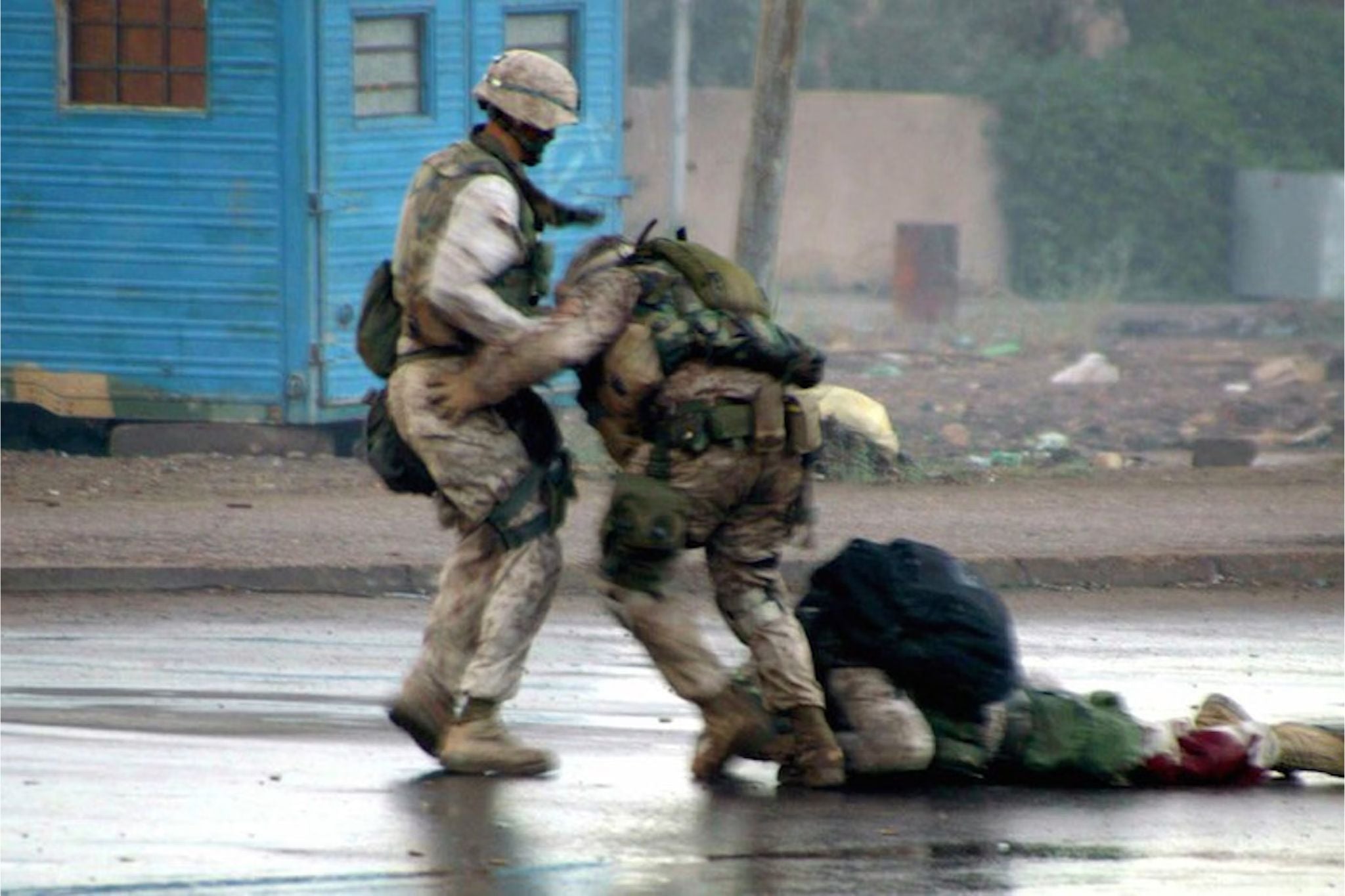 Two U.S. Marines rush to aid a wounded Marine lying on the rain-soaked streets of Fallujah during the Second Battle of Fallujah in Iraq.