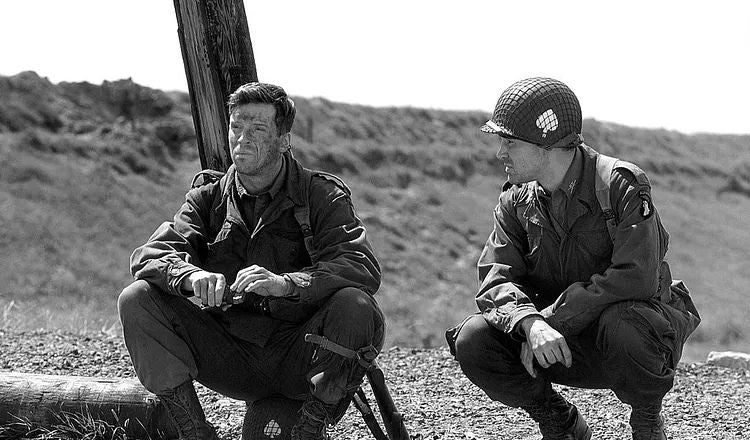 Actors Damian Lewis and Ron Livingston as World War II paratroopers in HBO’s Band of Brothers, seated together in a black-and-white scene.
