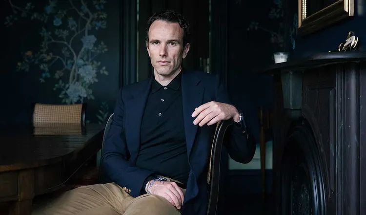 Portrait of Elliot Ackerman seated in a dark, wood-paneled room