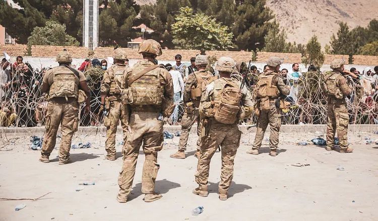 U.S. military personnel stand near a crowd of Afghan civilians behind concertina wire during the evacuation at Kabul airport following the fall of Afghanistan in 2021.