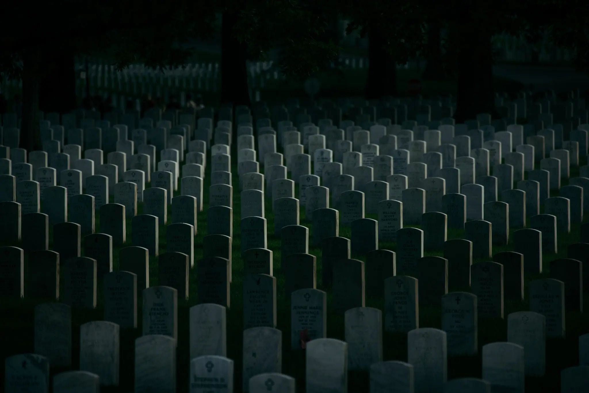 Rows of white headstones stretch across Arlington National Cemetery at dusk, symbolizing the sacrifice, remembrance, and enduring bonds among America's fallen service members.
