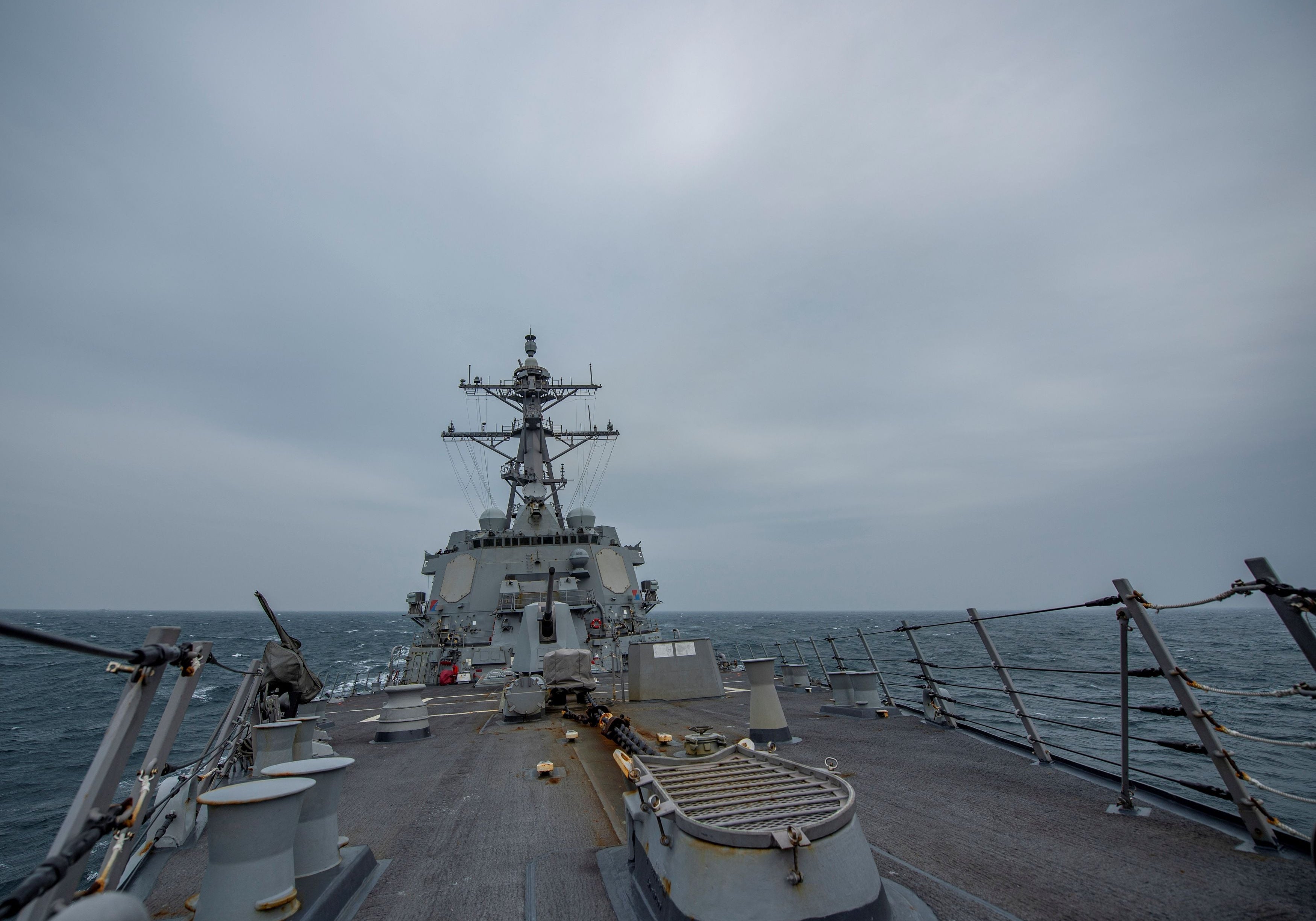 View from the deck of a U.S. Navy destroyer bow at sea under overcast skies.