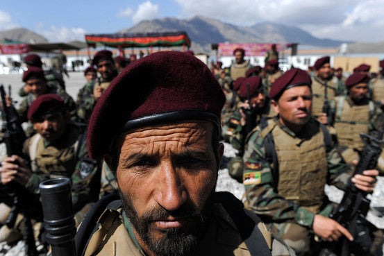 Afghan National Army soldiers in maroon berets stand in formation with mountains in the background.