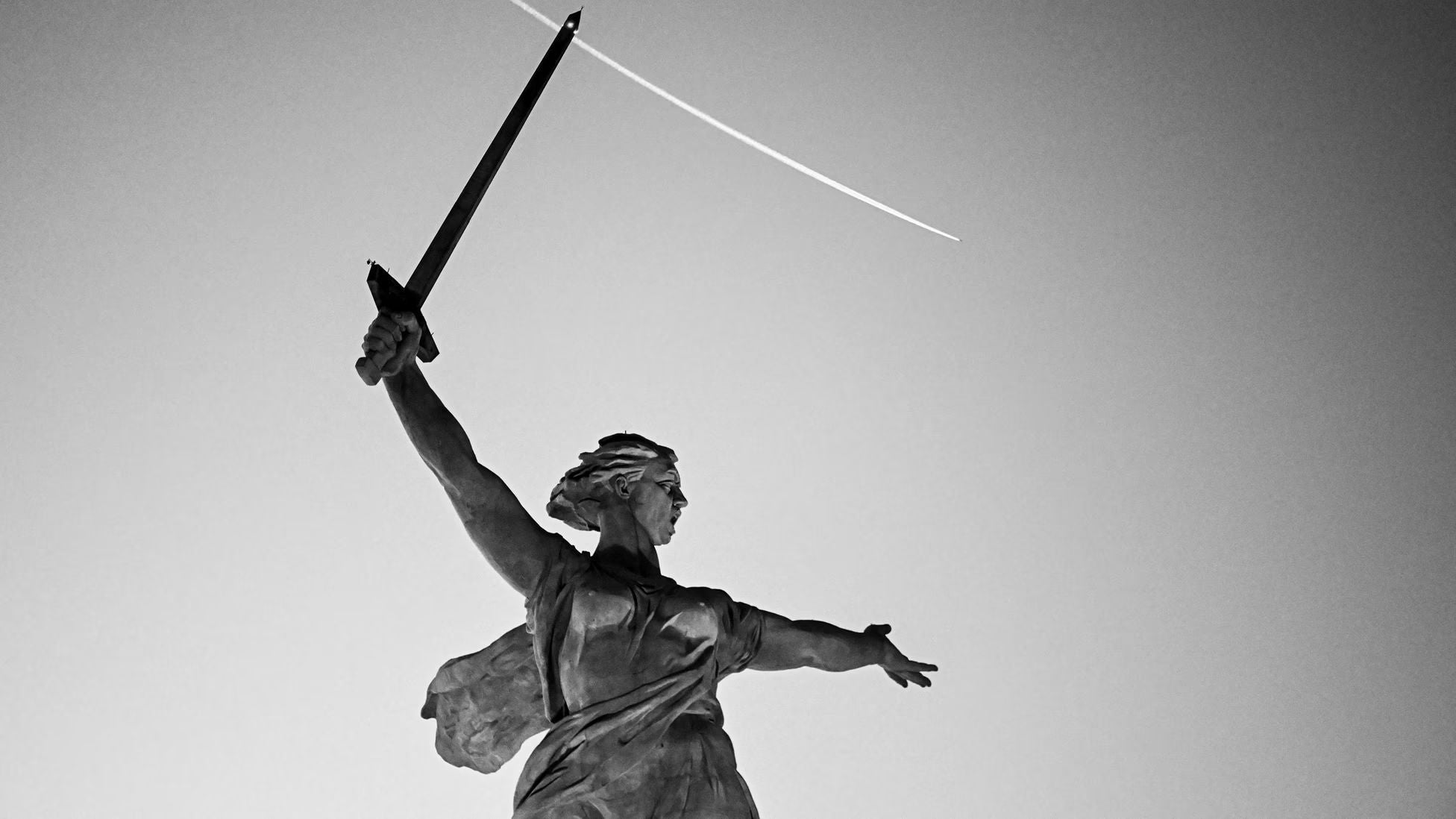 Black-and-white photograph of the Motherland Calls statue in Volgograd, Russia, raising a sword toward the sky, symbolizing the Battle of Stalingrad
