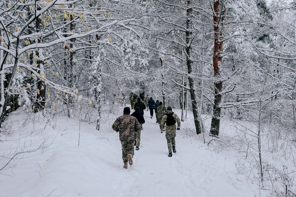 Ukrainian soldiers move through a snow-covered forest during winter training or military operations, illustrating the harsh conditions of cold-weather warfare.