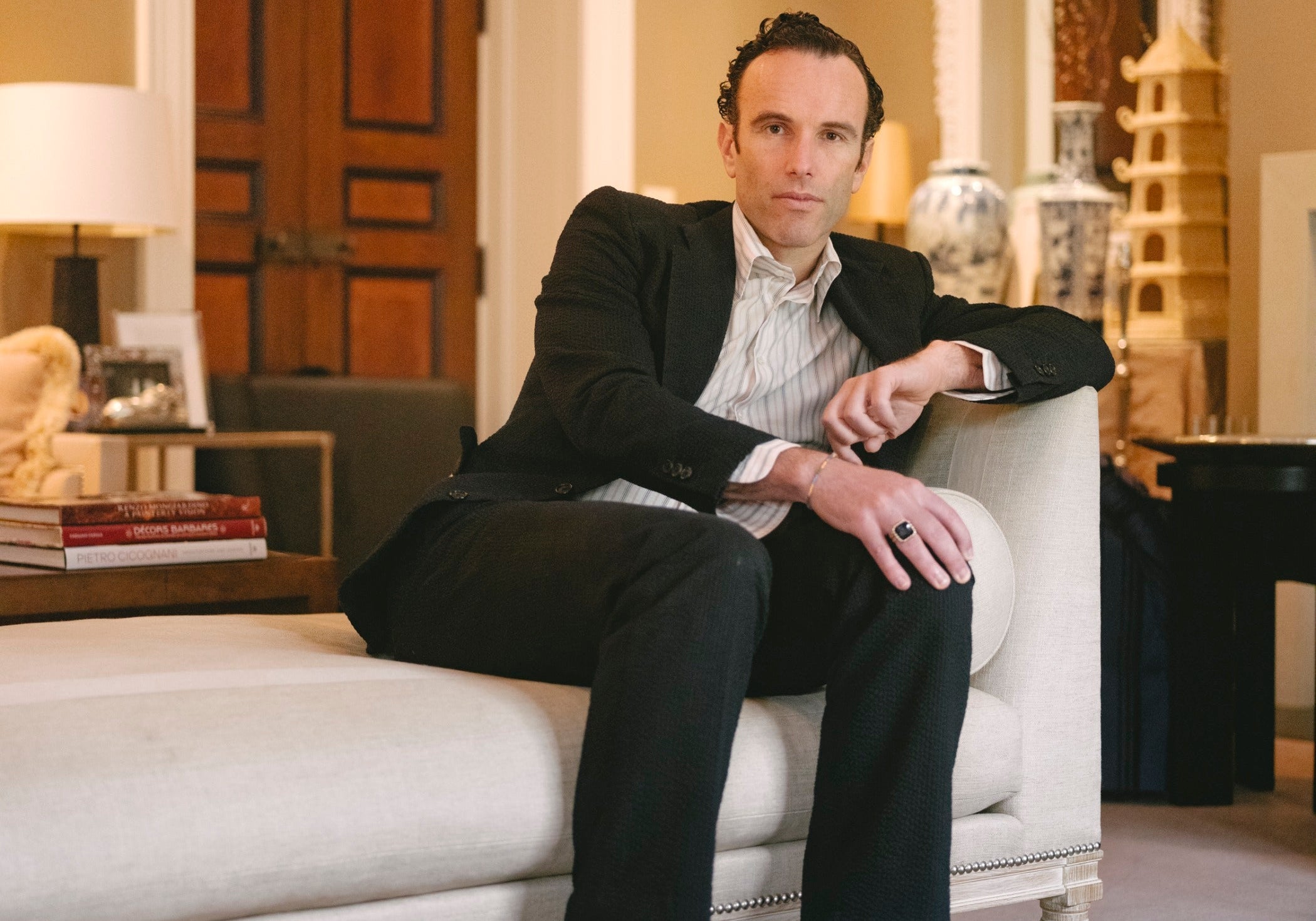 Portrait of author Elliot Ackerman seated in a chaise in a well-appointed living room.