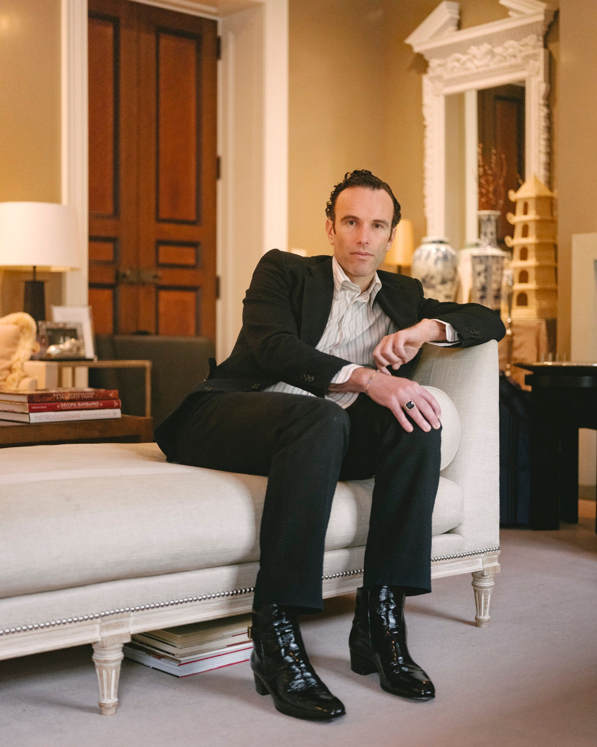 Portrait of author Elliot Ackerman seated in a chaise in a well-appointed living room.